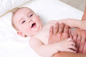 Mother massaging body of newborn baby - indoors